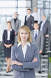 Portrait of confident businesswoman in suit with business people in background