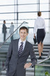 Portrait of confident businessman in suit leaning on railing in lobby