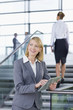 Smiling businesswoman in suit using digital tablet in lobby