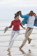 Smiling young couple running on beach