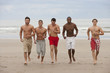 Photo : Smiling young men running bare chested on beach Smiling young men running bare chested on beach
