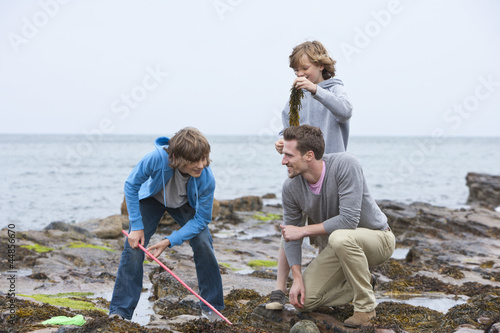 Photo: Father and sons playing with seaweed on rocks Father and sons playing with seaweed on rocks