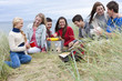 Teenage friends enjoying barbecue in grass on beach