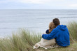 Teenage couple hugging in grass and looking at ocean view