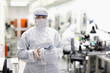 Foto: Portrait of scientist in clean suit carrying container in silicon wafer manufacturing laboratory Portrait of scientist in clean suit carrying container in silicon wafer manufacturing laboratory