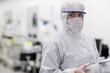 Foto: Portrait of scientist in clean suit carrying container in silicon wafer manufacturing laboratory Portrait of scientist in clean suit carrying container in silicon wafer manufacturing laboratory