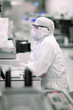 Photo: Scientist in clean suit working at computer in silicon wafer manufacturing clean room Scientist in clean suit working at computer in silicon wafer manufacturing clean room