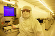 Photo: Portrait of scientist in clean suit working at computer in silicon wafer manufacturing clean room Portrait of scientist in clean suit working at computer in silicon wafer manufacturing clean room
