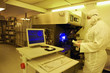Photo: Engineer in clean suit examining silicon wafer at computer in clean room laboratory Engineer in clean suit examining silicon wafer at computer in clean room laboratory