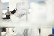 Photo: Scientist in clean suit examining silicon wafer under microscope in clean room laboratory Scientist in clean suit examining silicon wafer under microscope in clean room laboratory