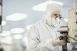 Photo: Scientist in clean suit using microscope in silicon wafer manufacturing laboratory Scientist in clean suit using microscope in silicon wafer manufacturing laboratory