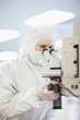 Photo: Scientist in clean suit using microscope in silicon wafer manufacturing laboratory Scientist in clean suit using microscope in silicon wafer manufacturing laboratory