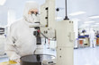 Photo: Scientist in clean suit using microscope in silicon wafer manufacturing laboratory Scientist in clean suit using microscope in silicon wafer manufacturing laboratory