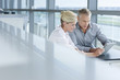 Businessman and businesswoman using digital tablet at office window