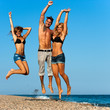 Energetic friends jumping on beach.