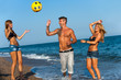 Three friends playing with ball on beach.