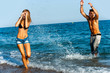 Young attractive couple splashing water at sea side.