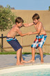 Photo: Kinder spielen am Swimmingpool - Jungen stoßen sich in den Pool Kinder spielen am Swimmingpool - Jungen stoßen sich in den Pool
