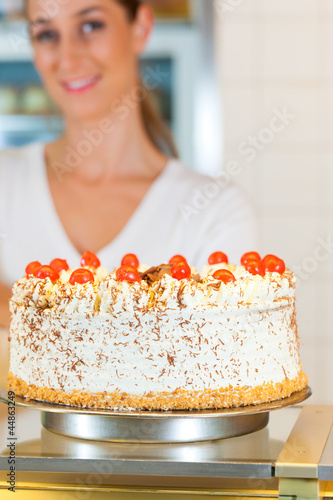 Photo: Bäckerin oder Konditorin mit einer Torte Bäckerin oder Konditorin mit einer Torte