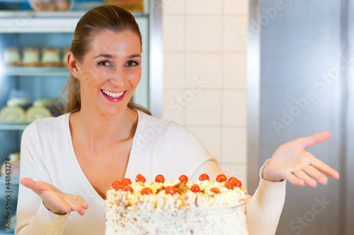Photo: Bäckerin oder Konditorin mit einer Torte Bäckerin oder Konditorin mit einer Torte