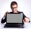 man sitting at office desk with laptop pointing