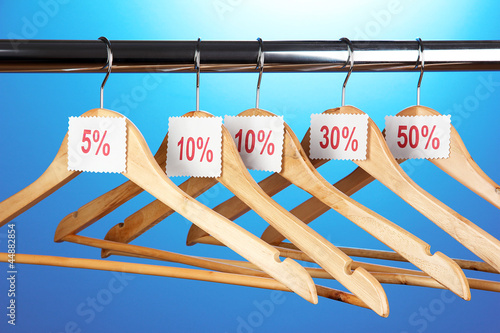 Photo: wooden clothes hangers as sale symbol on blue background. wooden clothes hangers as sale symbol on blue background.