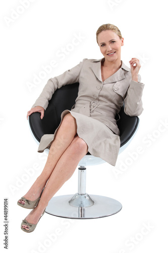 Photo: Woman in a suit sitting in a designer swivel chair Woman in a suit sitting in a designer swivel chair