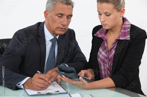 Photo: Businessman and woman using a calculator Businessman and woman using a calculator