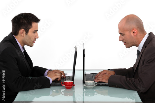 Photo: Profile of businessmen working at their laptops Profile of businessmen working at their laptops