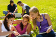 Teens studying in park reading book students