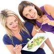 Photo: Two female friends sharing a plate of healthy leafy green salad Two female friends sharing a plate of healthy leafy green salad
