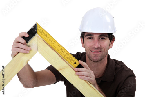 Photo: Man using setsquare on wooden frame Man using setsquare on wooden frame