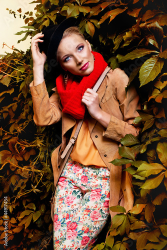 Photo: blonde woman wearing autumn clothes against wall of leaves blonde woman wearing autumn clothes against wall of leaves