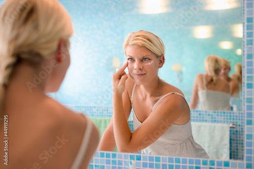 Photo: Female beauty, young woman applying lotion on face at home Female beauty, young woman applying lotion on face at home