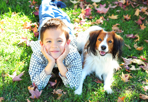 Photo: Young Boy and a Dog Lying on the Grass Young Boy and a Dog Lying on the Grass