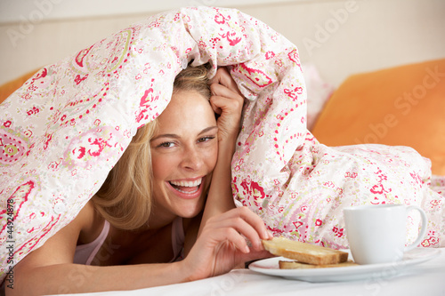 Photo: Pretty Woman Snuggled Under Duvet Eating Breakfast Pretty Woman Snuggled Under Duvet Eating Breakfast