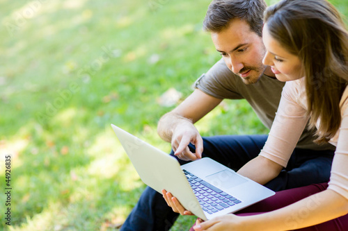 Photo: Couple using a laptop outdoors Couple using a laptop outdoors