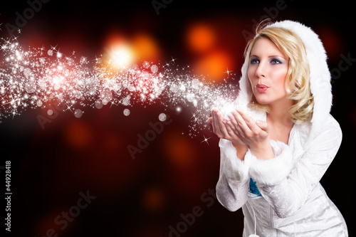 Photo: junge blonde Frau im Winteroutfit pustet Schnee junge blonde Frau im Winteroutfit pustet Schnee