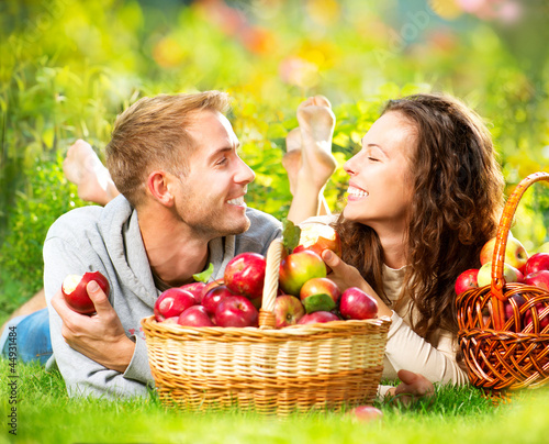 Photo: Couple Relaxing on the Grass and Eating Apples in Autumn Garden Couple Relaxing on the Grass and Eating Apples in Autumn Garden