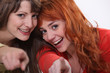 Two female friends pointing at the camera.