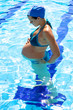Gorgeous pregnant female model in swimmingpool looking belly