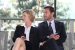 Business executives sitting on a bench texting