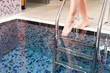 Junge Frau steigt in ein Wasserbecken