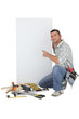 Handyman pointing to a blank sign