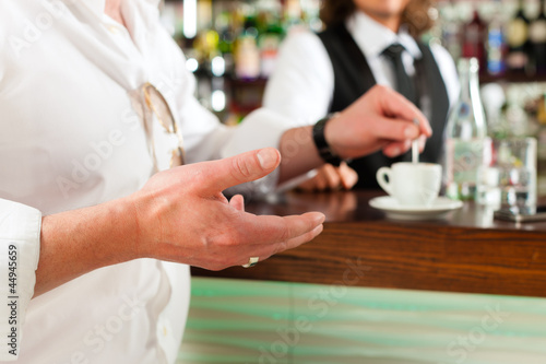 Photo: Barista with client in his cafe or coffeeshop Barista with client in his cafe or coffeeshop