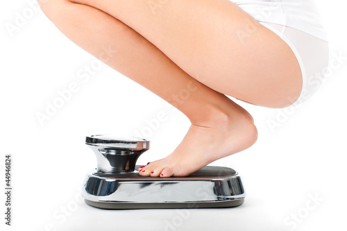 Photo: Young woman sitting on her haunches on a scale Young woman sitting on her haunches on a scale