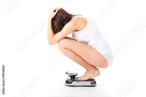 Photo: Young woman sitting on her haunches on a scale Young woman sitting on her haunches on a scale