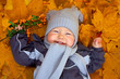 happy baby boy lies among fallen leaves