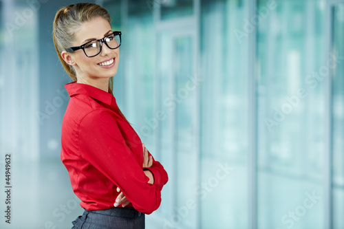 Photo: Young businesswoman against office windows. Young businesswoman against office windows.