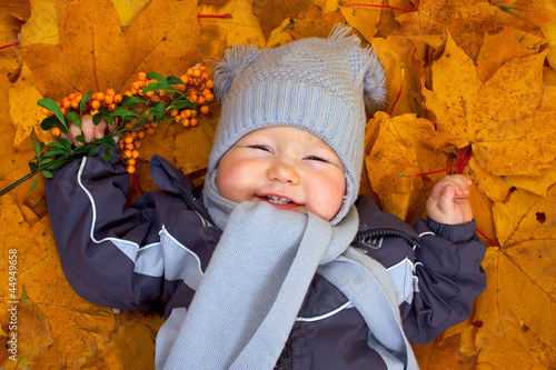 Photo: happy baby boy lies among fallen leaves happy baby boy lies among fallen leaves